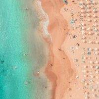 an aerial view of a beach with umbrellas and chairs